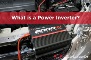 Schumacher power inverter hooked up and perched on the open hood of a car.